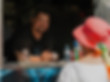 A person in a food truck window leaning out to help a person with a red hat.