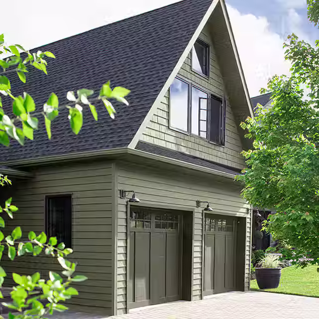 A green house with a dark green garage door color, Gravel Gray by Benjamin Moore.