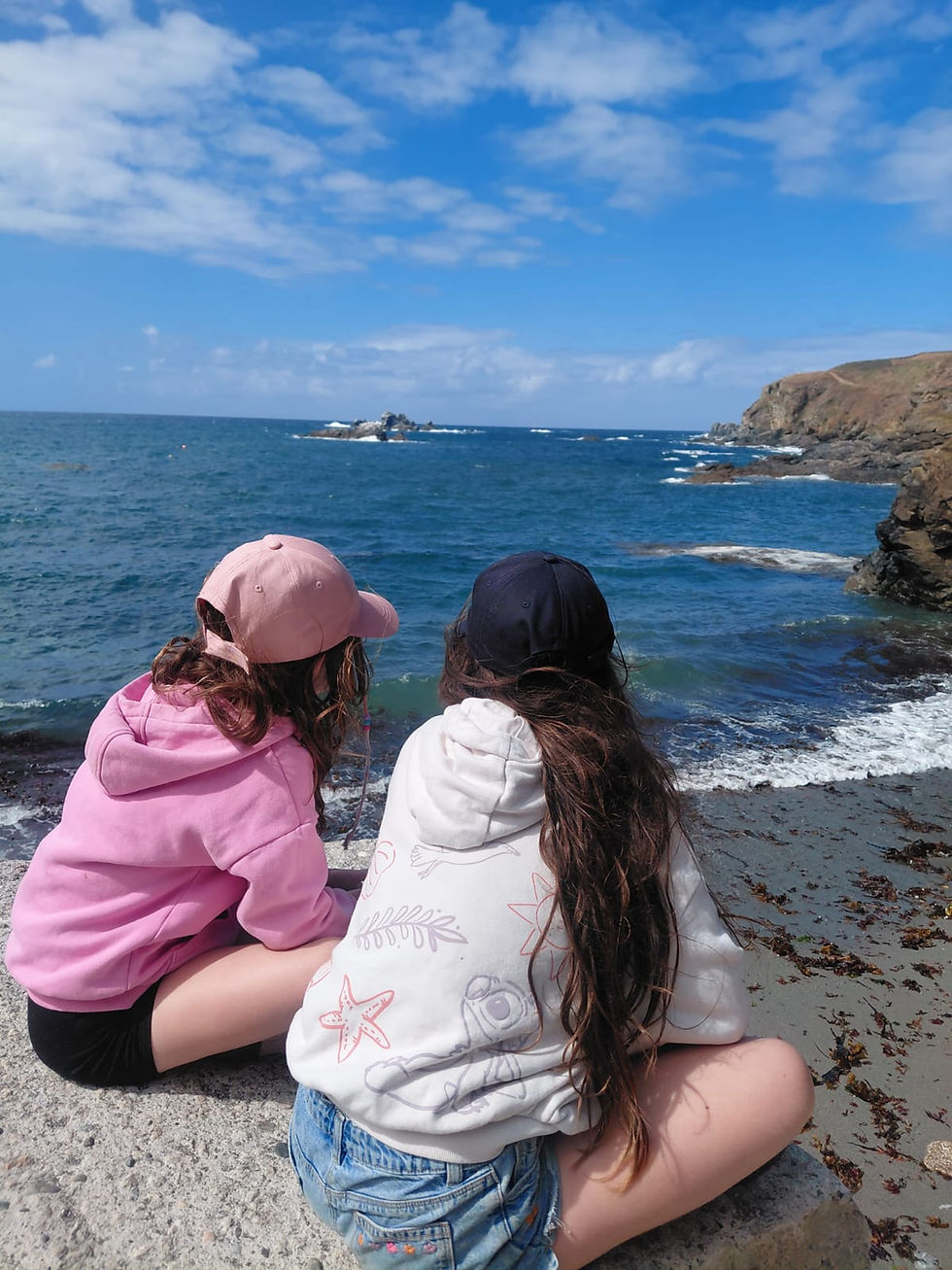 two young girls looking out to the sea with their backs to the camera