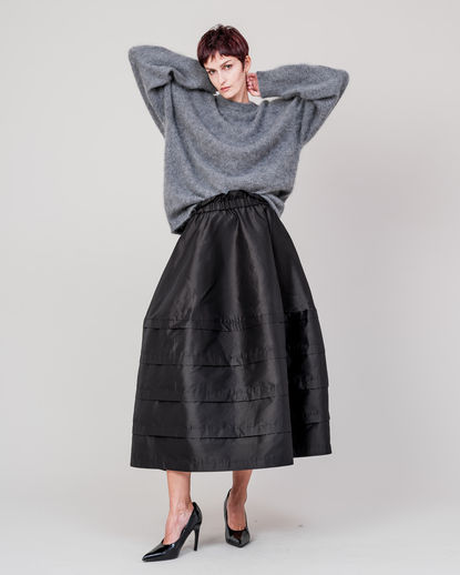 Shiny tucked skirt with a subtle reflective surface and structured volume. Fine tucks create a clean, modern silhouette with soft movement. DOMELLE 25AW look.