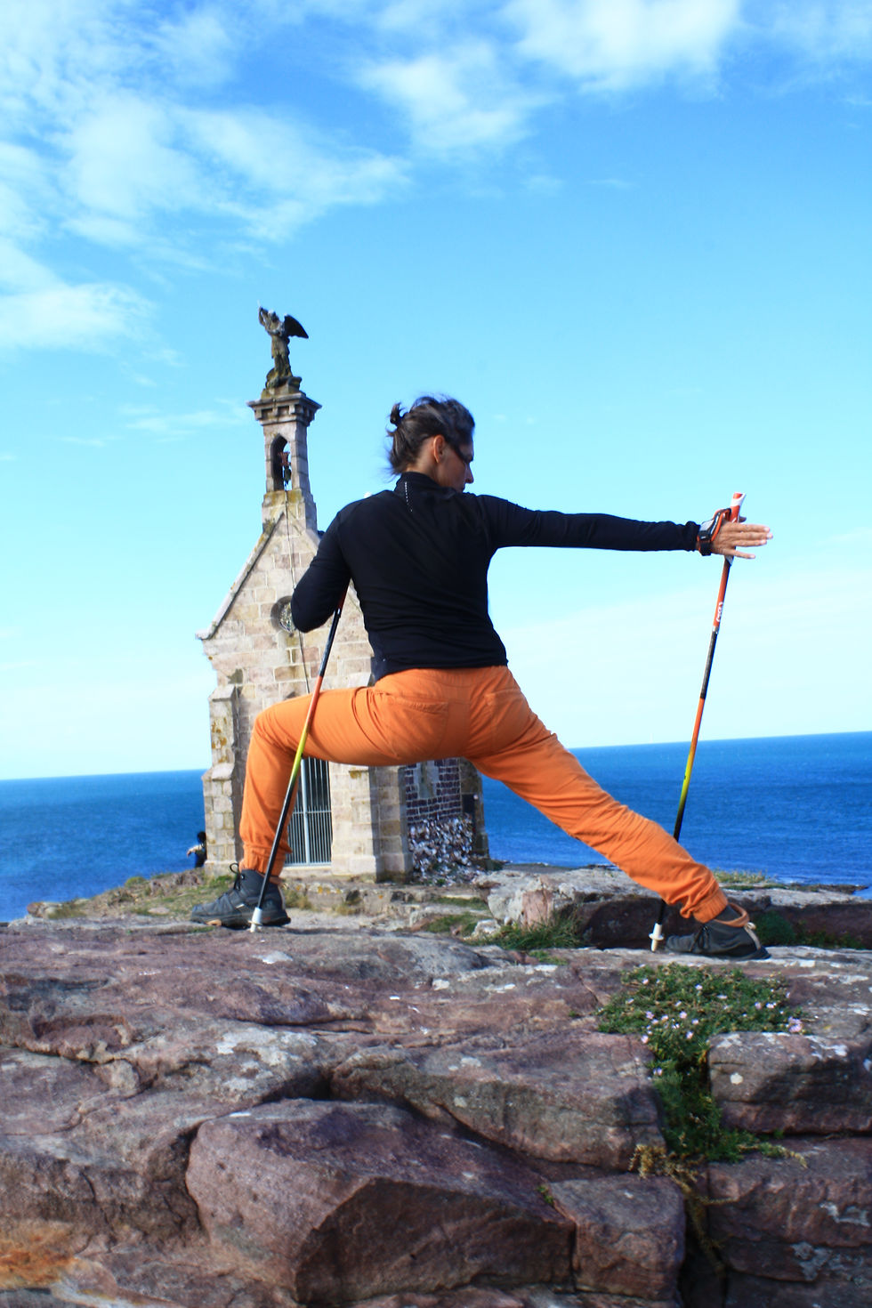 Françoise Le Clerc pratiquant le Nordic Yoga® face à la mer en Baie de Saint-Brieuc, bâtons de marche nordique en main