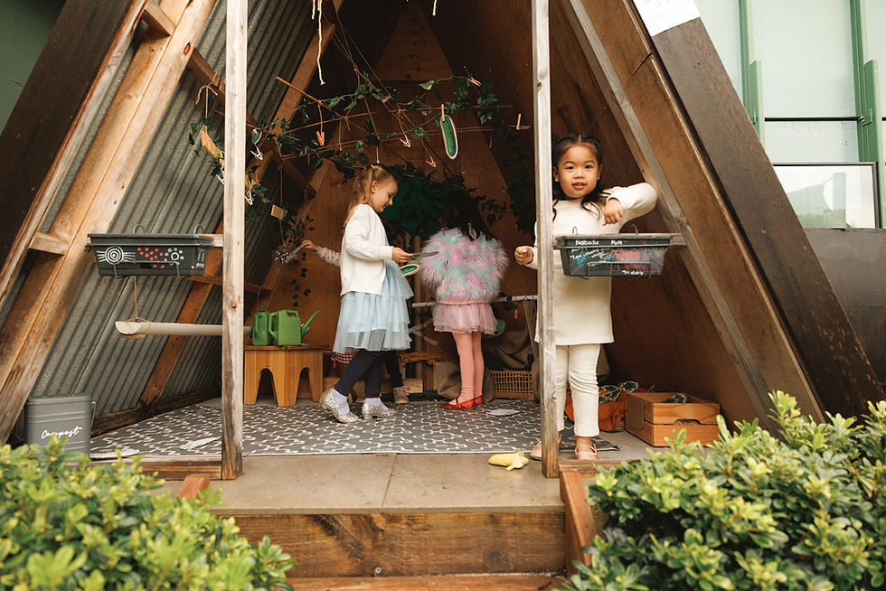 Children playing inside A-frame playhouse holding items and interacting together for fun.