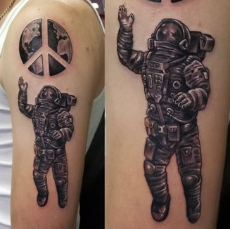 black and grey astronaut tattoo on bicep