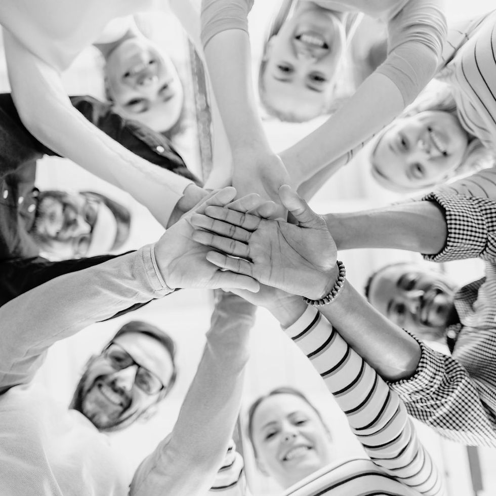 Group of diverse creatives stacking hands in solidarity.