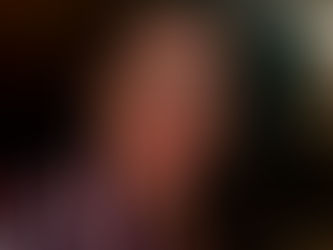 Kassandra smiling at the camera with long, dark hair, wearing a red, black and white striped shirt.