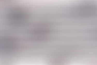 Pedestrians cross a wide zebra crossing in an urban setting, casting long shadows in the bright sunlight.