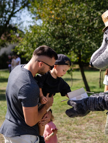 Maskottchen verteilt Flyer an Familie beim Hofmarkt-und-Familienfest