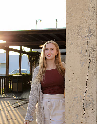 Catholic wedding photographer smiles at camera in front of scenic coffeeshop in Weslaco, Texas