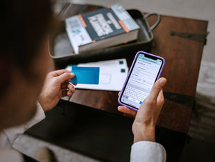 Looking over the right shoulder of person using a credit card with a phone