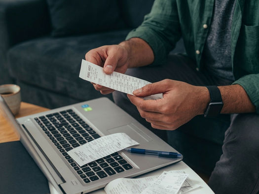 Person holding a receipt sitting at a computer