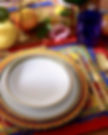 Dining place setting featuring Dolce&Gabbana Casa's Carretto Siciliano collection with underplate, dinner plate and pasta bowl, alongside gold coloured cutlery and a patterned placemat.