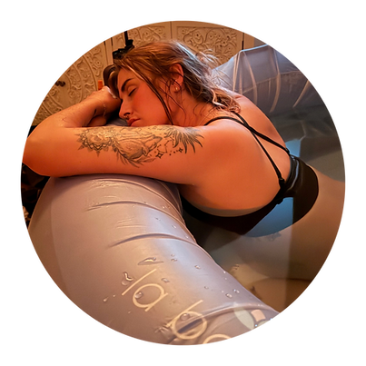 woman in labour with tattoos leaning over the edge of a birth pool 