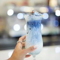 Es una mano sujetando una bebida Matcha de color azul. 