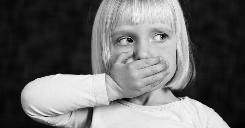 Black and white image of a girl covering her mouth