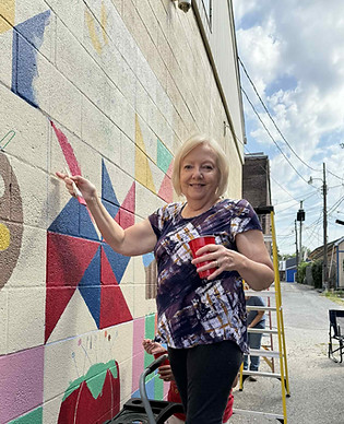 An image of a woman painting a community paint-by-numbers mural.