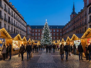 Ambiente navideño en un mercadillo iluminado de Madrid, con casetas decoradas y luces festivas al anochecer.
