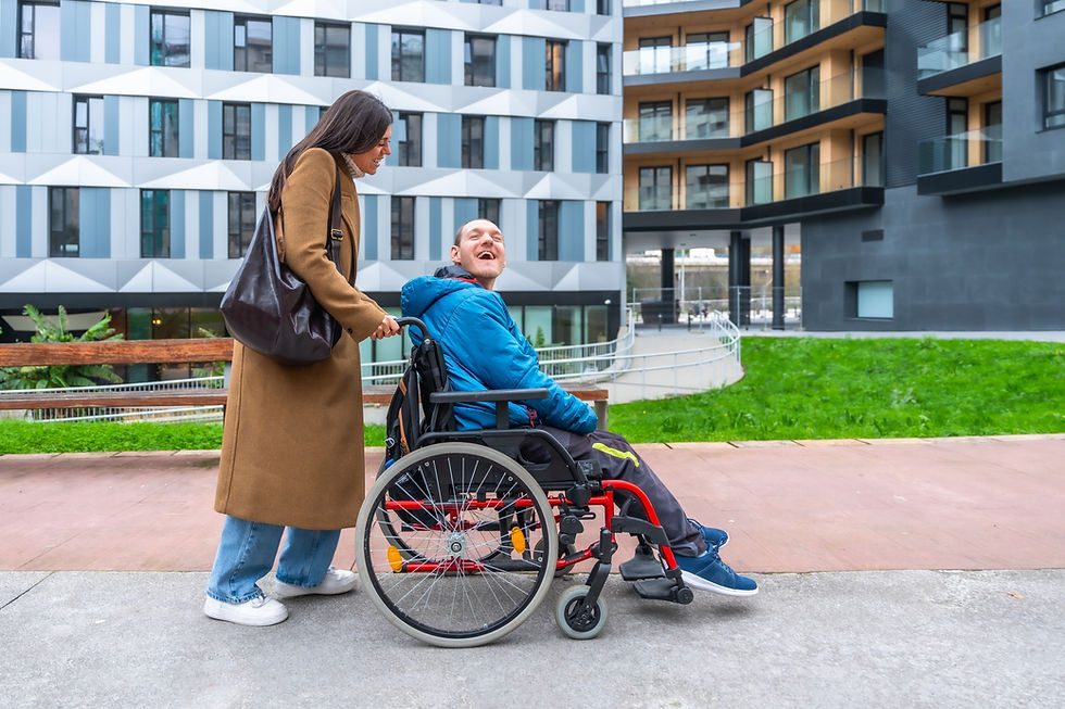 Caregiver pushing a happy adult man with a disability in a wheelchair, enjoying time outdo