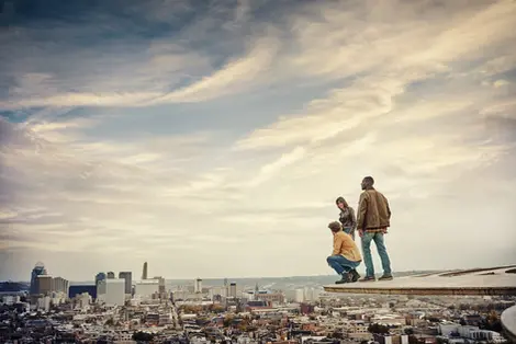 People in casual outdoor clothing standing on an overlook above a city. Captured by Thomas Hoeffgen.