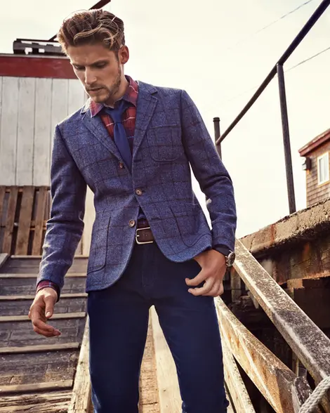 Man in a tailored blue blazer and dark trousers on a wooden dock. Shot by Thomas Hoeffgen.