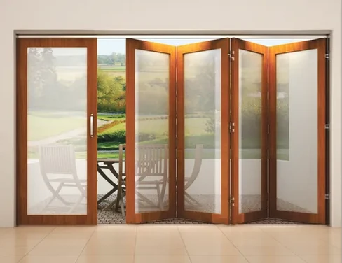 Elegant folding wooden doors with large frosted glass panels opening to a patio seating area by a wooden doors with glass panels manufacturer in Ahmedabad, Gujarat.