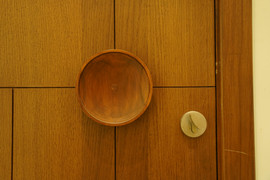 Close-up of modern veneer wooden door with circular wooden handle and metal knob, crafted by veneer door and frame manufacturers Ahmedabad, Gujarat.