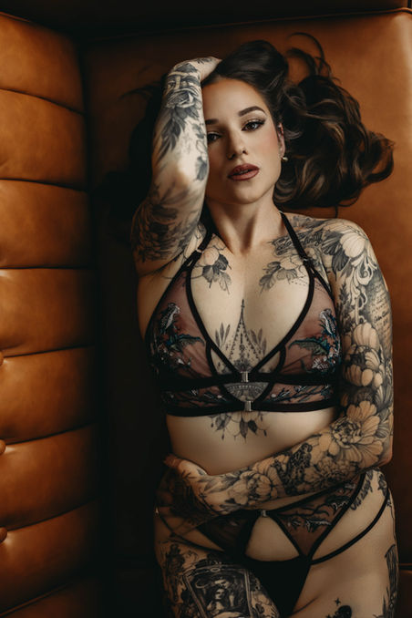 Boudoir portrait of woman lying on leather sofa in moody Alaska studio