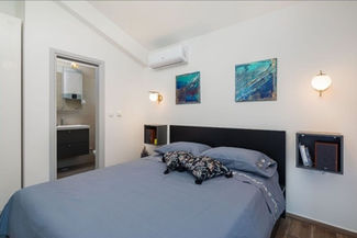A small bedroom with a queen-sized bed with a  blue comforter. 