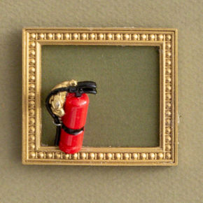 Closeup of miniature fire extinguisher in a gold frame.