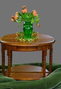 Closeup of miniature end table with green vase and orange flowers.