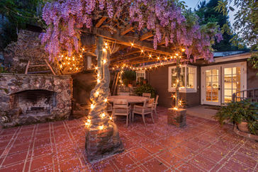 Backyard of a home on Lookout Mountain at twilight, featuring a cozy seating area and a central tree adorned with ambient string lights for an inviting atmosphere.