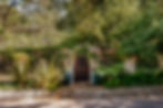 Gated front entry of a Fryman Estates property featuring a wood and steel door set among mature landscaping