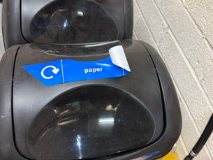 Sticker peeling from plastic waste bin due to poor adhesion.