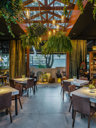 Projeto arquietônico de bar/restaurante com bantante material natural e plantas assinado pelo escritório Anna Paula Melo Arquitetura