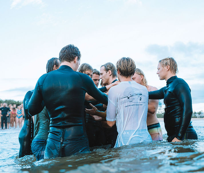 A group of surfers praying for their friend