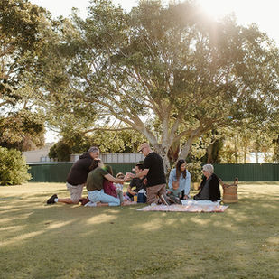Group of people having a picnic in a grassed outdoor area with lovely afternoon light