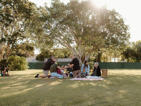 Group of people having a picnic in a grassed outdoor area with lovely afternoon light