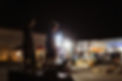 Two teenage boys standing on a mid-height skate ramp, at night with lights shining and youth gathered