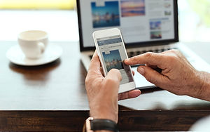 Hands touching a Mobile Phone with laptop in background