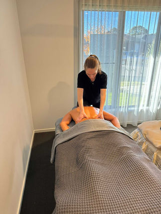 Licensed therapist providing a relaxing back massage in a serene room with natural sunlight, focusing on wellness and stress relief.