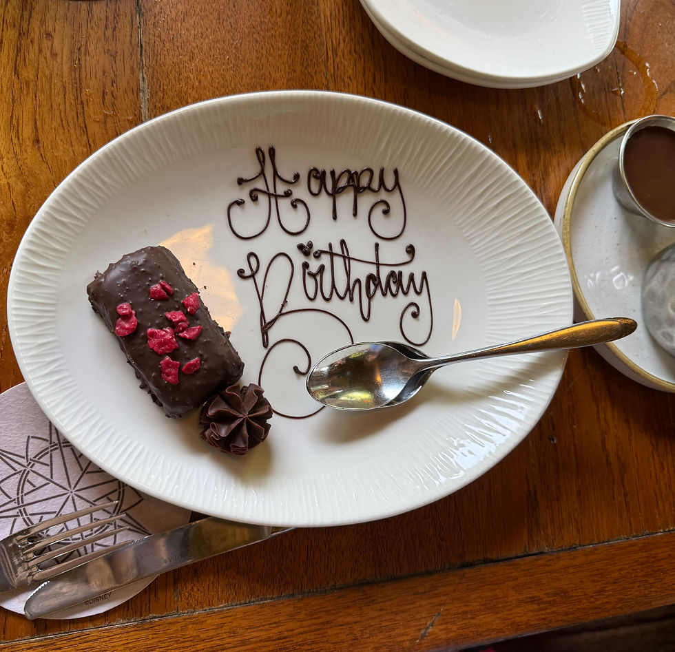 A sweet chocolate treat sits on a white plate with chocolate calligraphy that says "Happy Birthday"