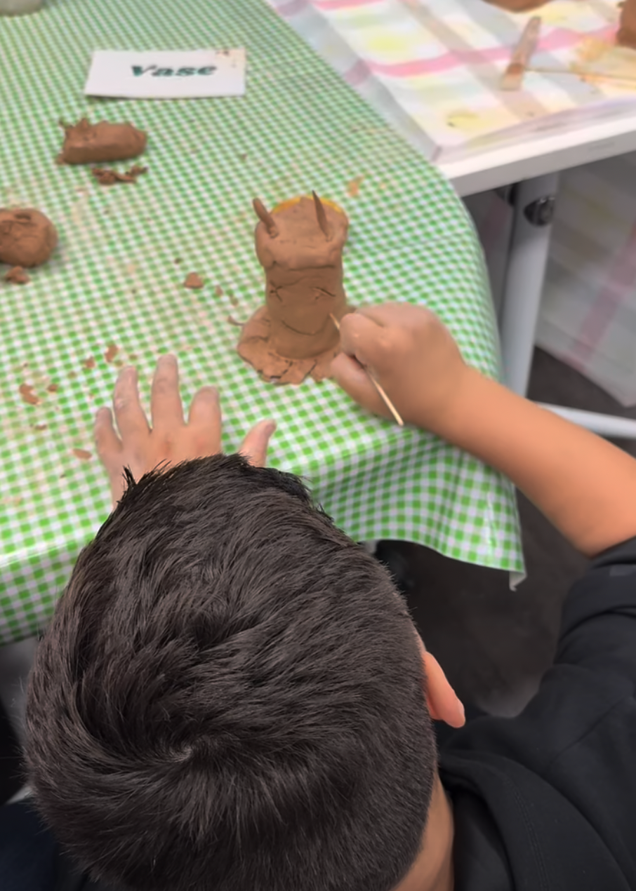 Boy etching design into a clay artwork
