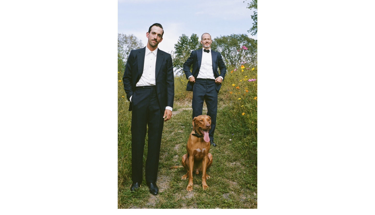 Two grooms standing outdoors with dog during intimate same-sex backyard wedding in Kingston, New York