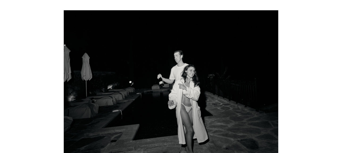 Black and white Hotel du Cap-Eden-Roc wedding afterparty with guests walking poolside at night carrying champagne on the French Riviera