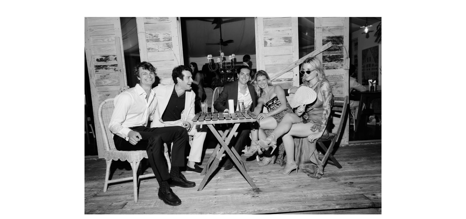 Black and white wedding afterparty at Other Side Hotel Bahamas with stylish guests gathered around a table in a relaxed coastal dinner party setting