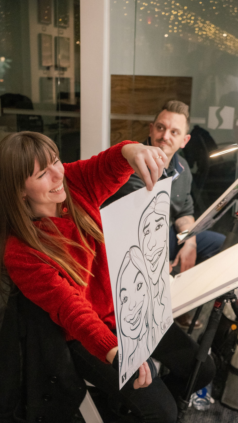 Caricature Artist working a Holiday Party and showing guests their caricatures.