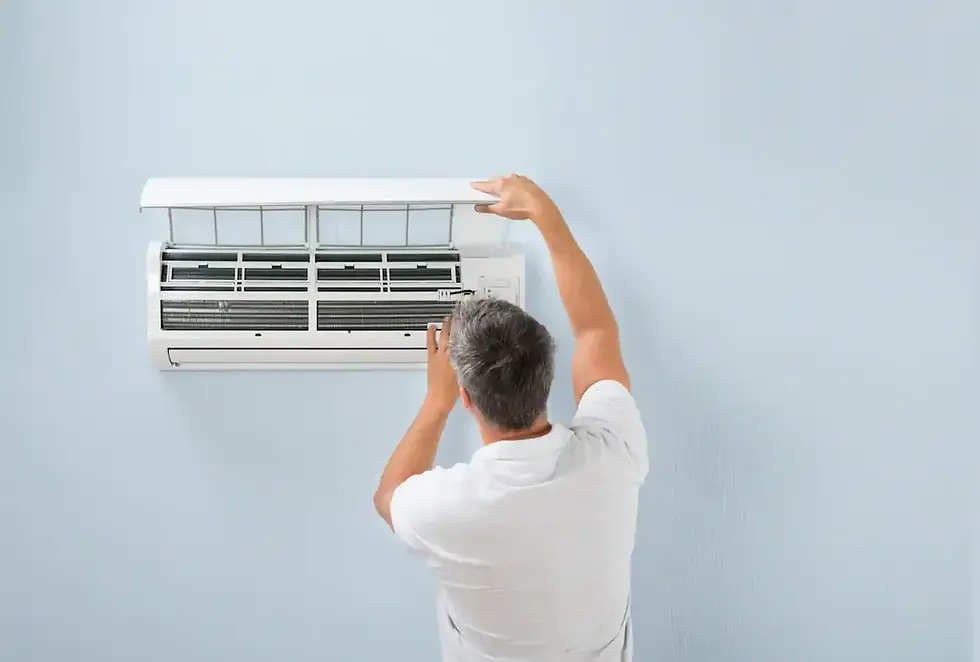 Man in white shirt fixes wall-mounted air conditioner against a light blue wall. The mood is focused and the setting is domestic.