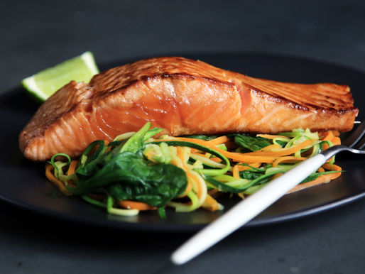 Grilled salmon fillet served on a bed of spiralized vegetables with a lime wedge on the side, ready to be enjoyed.