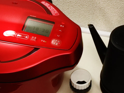 A sleek, red electric bread maker is displayed on a countertop, accompanied by a stylish black electric kettle, showcasing a modern kitchen appliance setup.