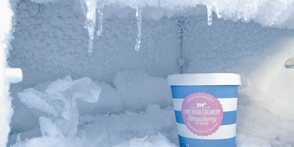 A blue and white ice cream tub labeled "Lewis Road Creamery, Strawberry" sits in a frosty freezer with icicles and snow.