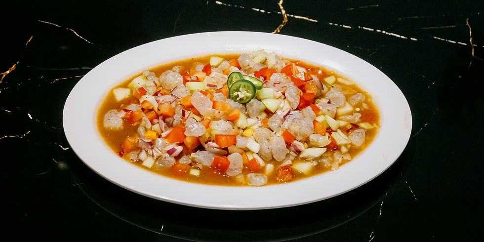 A plate of colorful ceviche with shrimp, diced vegetables, and jalapeño slices on a dark, glossy marble table.